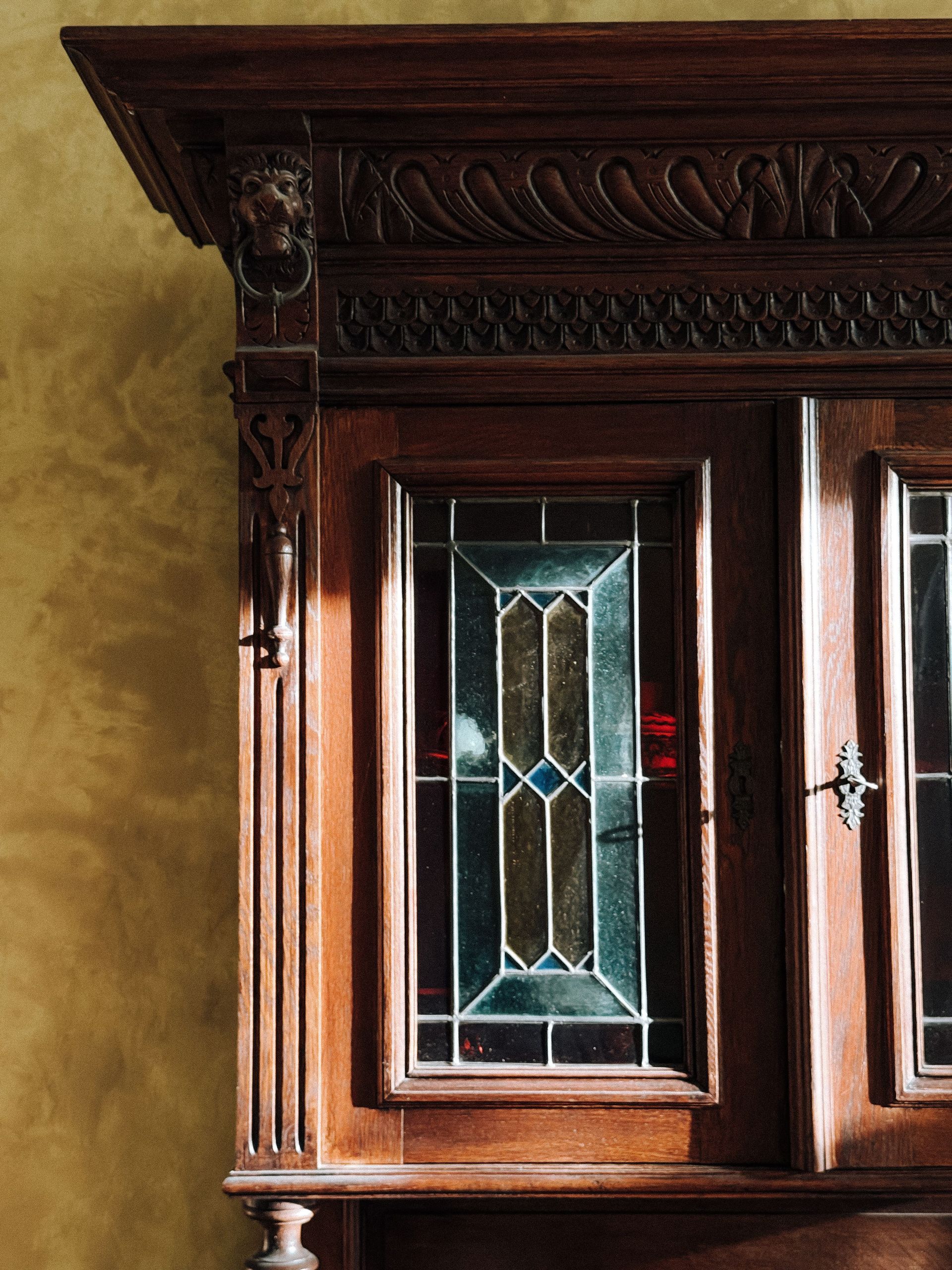 Close-up of an antique wooden cabinet displaying intricate stained glass panels and ornate carvings.
